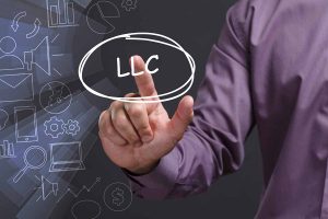 A young businessman shows the word: LLC on virtual screen.
