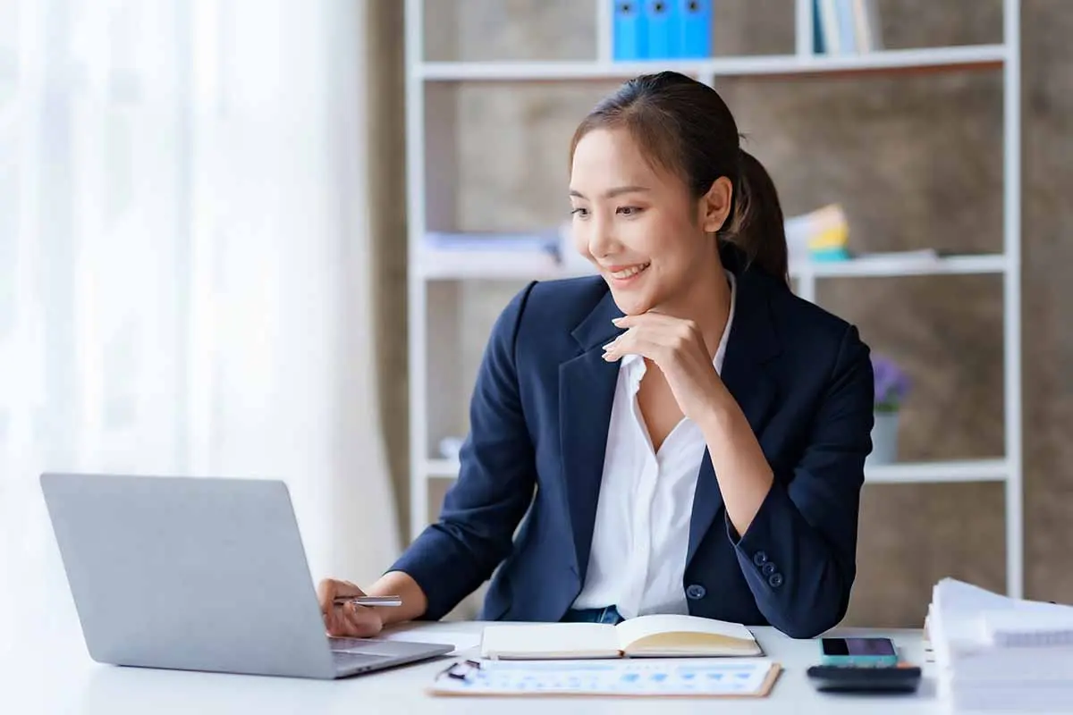 Asian business owner reviewing LLC reinstatement documents while working from office desk