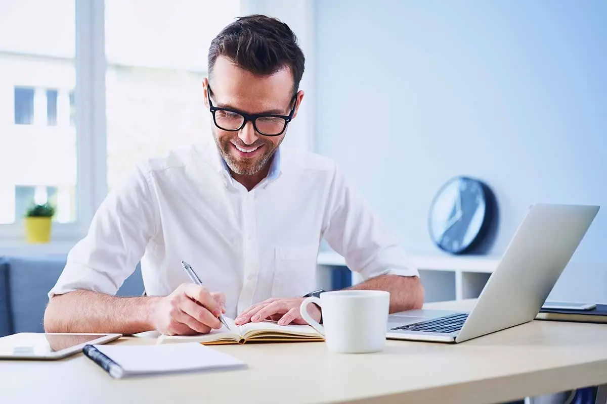 Business owner reviewing documents and working on a laptop while preparing an LLC ownership change.